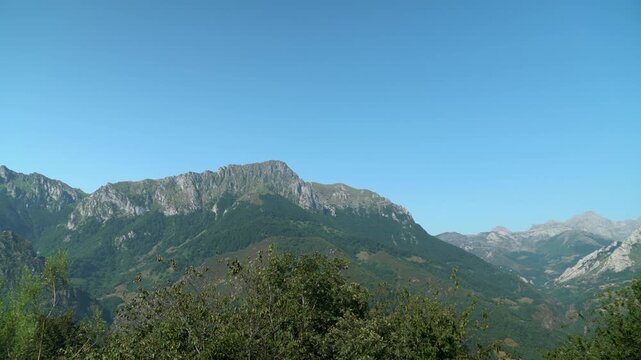 Paisaje monta&ntilde;oso de Asturias con cumbres verdes, valles y naturaleza exuberante bajo un cielo azul, reflejando la belleza salvaje del norte de Espa&ntilde;a.
