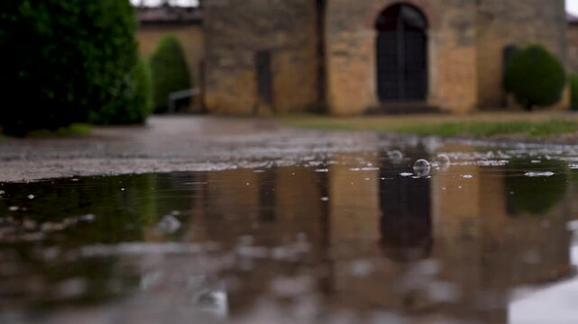 Detalle del suelo mojado en un d&iacute;a de lluvia en Oviedo, donde el reflejo de la Iglesia de San Juli&aacute;n de los Prados aparece sobre el empedrado entre charcos.