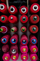 Fototapeta premium Rows of red and pink thread spools fill the frame, showing a bold pattern of sewing supplies with colorful accent centers