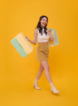 Asian woman walking with colorful shopping bags expressing retail excitement consumer confidence seasonal sales fashion freedom and a joyful modern shopping lifestyle.