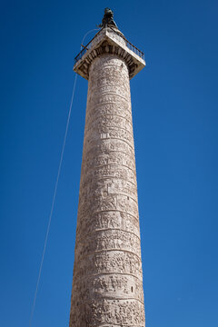 Monumental vertical view of the ancient Roman Column of Trajan with reliefs under clear blue sky in Rome, Italy