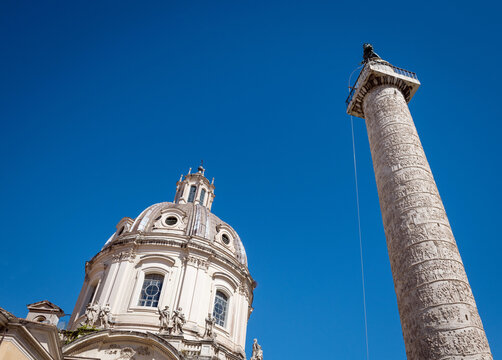 The ancient Column of Trajan and the beautiful dome of Santissimo Nome di Maria church against clear blue sky in Rome, Italy