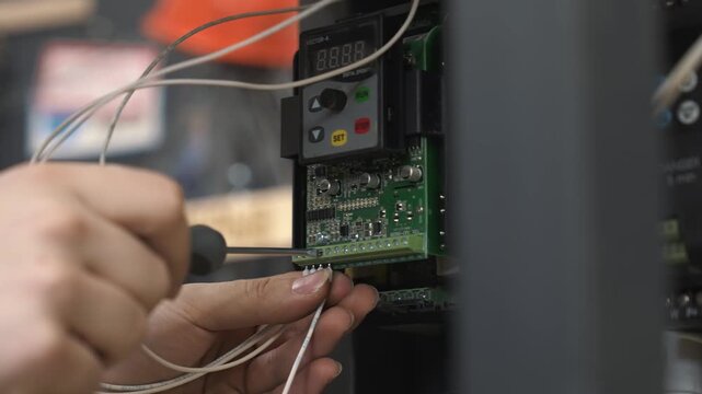 An electrical engineer connects wires and plugs them into a junction box with a microchip