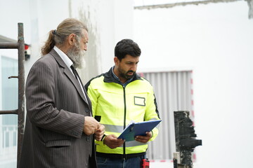 Obraz premium Construction Engineer Discussing Site Inspection Report with Investor at Construction Site