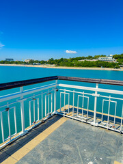 Fototapeta premium View of a pier showing water, buildings, and a clear sky during the daytime near a coastal area with a beach in the background