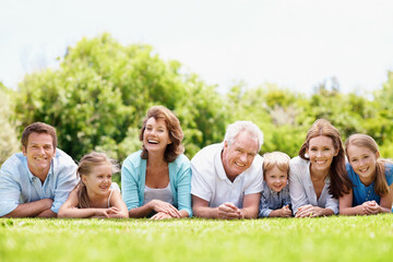 Obraz premium Portrait, family and parents in park with children, relax together and generations bonding on weekend. Happy, mature people and grandma outdoor on grass with grandfather, kids and rest for wellness.
