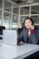 Fototapeta premium Busy woman sitting in the office and having a phone call