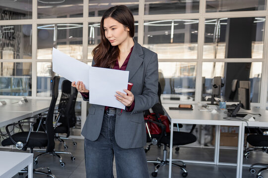 Smiling young woman holding documents in hands and looking contented