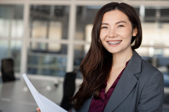 Smiling young woman holding documents in hands and looking contented