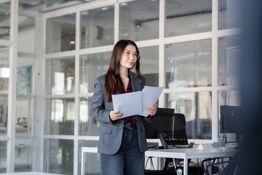 Young woman holding documents in hands and looking contented