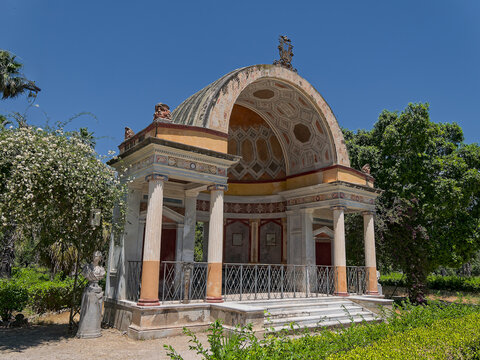 Elegant historic music stand in Villa Giulia gardens, Palermo, Italy. Beautiful view of the classic arcaded stone exedra featuring antique painted patterns and lush green foliage.