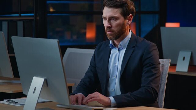 Concentrated Caucasian middle-aged business man working with computer thinking at evening pensive looking in desktop monitor adult mature male businessman company owner thoughtful work at night office