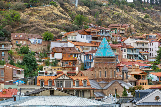 Cityscape of Tbilisi old town on a hill with a church, Georgia. Overcast weather with cloudy sky