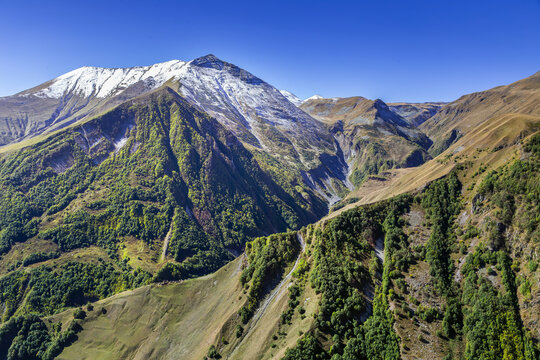 Mountain gorge view from Gudauri viewpoint in Georgia, deep canyon landscape of Caucasus. Sunny day with clear blue sky.
