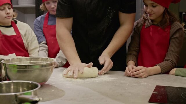 Unrecognizable male chef clapping hands with flour in slow motion during culinary workshop with children. Clip is perfect for promoting kids cooking classes and educational programs