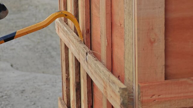 Breaking open wooden crate pallet style with crowbar, goods from courier service