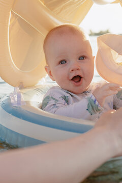 Joyful baby with blue eyes in a swim ring on a sunny day