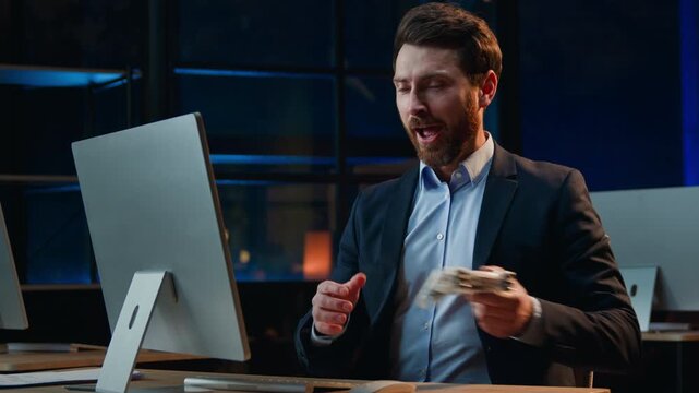 Funny Caucasian middle-aged business man computer work pause playing online game at night evening dark office male businessman looking around taking joystick play console winning continue working
