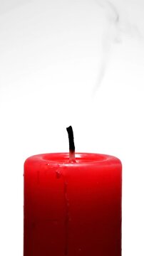 Extinguished red candle with white smoke trail on white background
