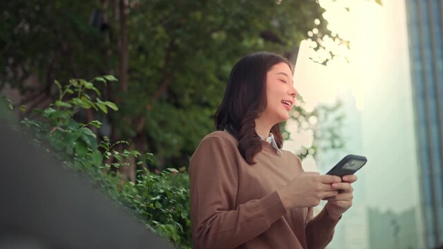 smartphone, typing, texting, female, asian, woman, smiling, urban, holding, mobile phone, cell phone, looking at phone, park, outdoor, city, business district, building, lifestyle, skyscraper, street,