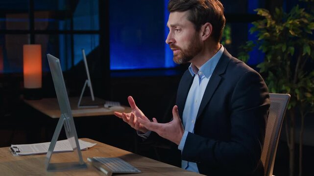 Professional Caucasian business man talking video call at late evening dark night office middle-aged businessman male boss talk computer conference communicating online negotiate distant coaching job