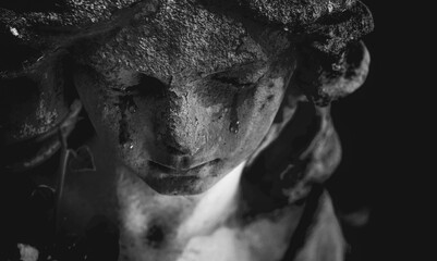 Fototapeta premium Black and white statue of a weeping angel with tear-stained face. A symbolic portrait expressing that angels mourn alongside humanity, representing compassion