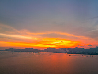 Obraz premium Beautiful golden hour drone image showcasing Phuket's coastal scenery, tranquil ocean, distant mountains, and breathtaking sunset over the tropical island.