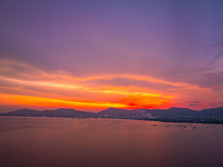 Obraz premium Spectacular drone photograph of Phuket's coastline during sunset, capturing the glowing horizon, peaceful sea, and colorful tropical sky over southern Thailand.