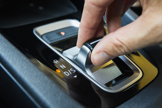 Close-up of a driver's hand shifting gears on a modern automatic car gear selector