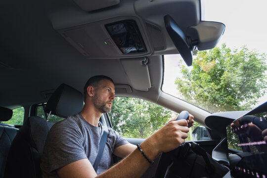 Side view of a confident man driving a modern car with both hands on the steering wheel