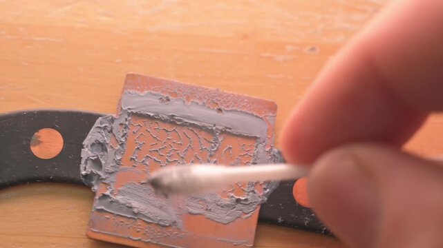 Technician cleaning old thermal paste from processor heatsink copper base close up macro shot emphasizing computer maintenance hardware repair services marketing campaign commercial technical content 