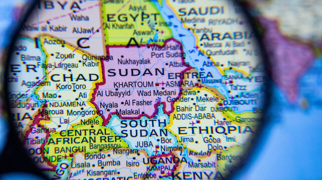 magnifying glass examining sudan and countries of the horn of africa on a global map.