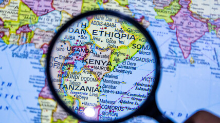 Magnifying glass examining map of east africa focusing on kenya and surrounding countries. © Photo Agency