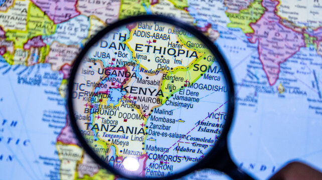 Magnifying glass examining map of east africa focusing on kenya and surrounding countries.