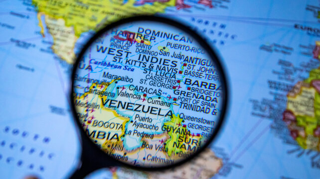Magnifying glass focusing on venezuela and caribbean islands on world map.