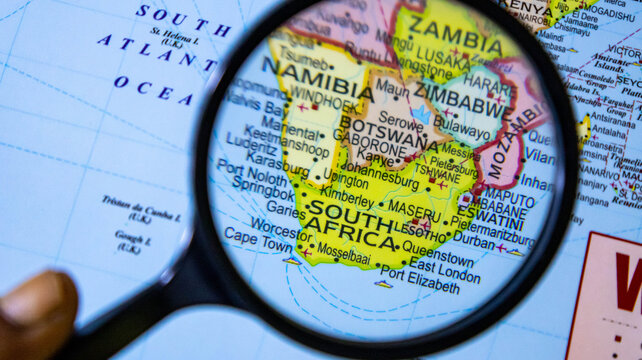 Magnifying glass positioned over south africa on paper world map for educational research.