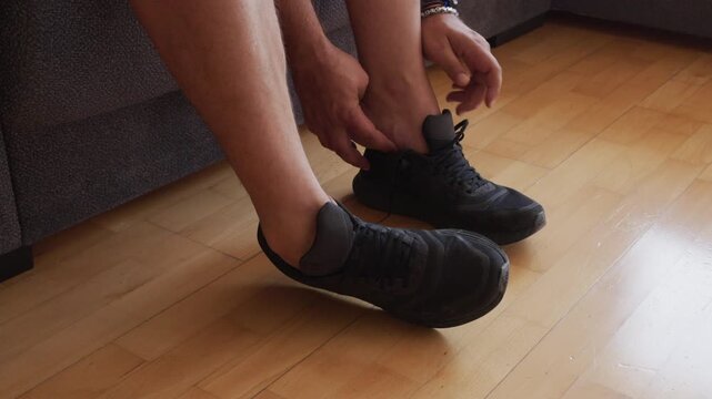 Man putting on and taking off black sneakers