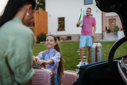Happy family leaving home for summer vacation with luggage and pool toys.