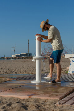 Man washing sandy feet at public beach foot shower