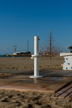 Public beach shower on wooden boardwalk by the sea