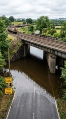 Fototapeta premium Freight train on a railway bridge over a flooded road