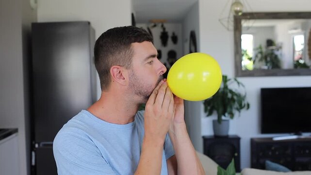 Exhausted adult inflating big yellow rubber balloon