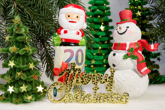 A large snowman with letters and Santa Claus standing on a euro banknote against a background of Christmas trees