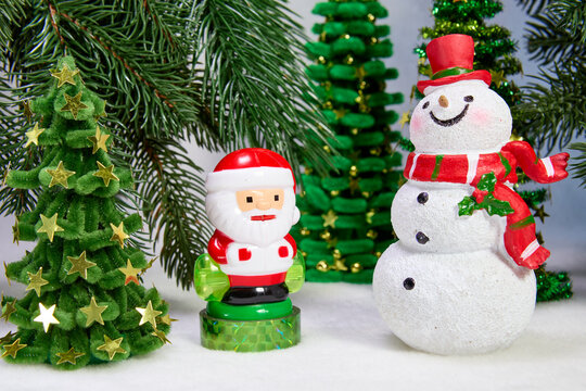 Little Santa Claus and a big snowman against the backdrop of Christmas trees