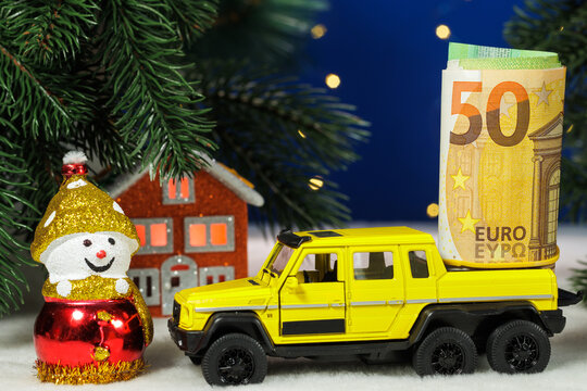 A snowman and a yellow car with euro bills in the back near an orange house under a Christmas tree