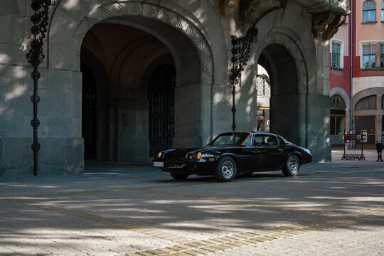 Chevrolet Camaro 2 gen (1978-1981 late, plastic bumper) - front three quarter view of black american muscle car parked near the historic stone arches of the City Hall in Subotica, Serbia. July 5, 2025