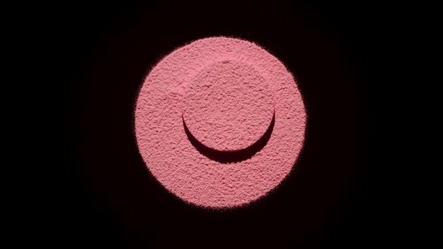 Overhead frame of red sifted powder in a circular shape with a smaller round platform at the center receiving orbiting light that projects shadows on black | Blush ad campaign concept