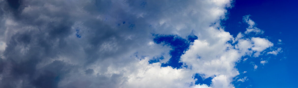 Clouds gather and shift across a bright blue sky in a rural area. The weather shows signs of change as the clouds move in.