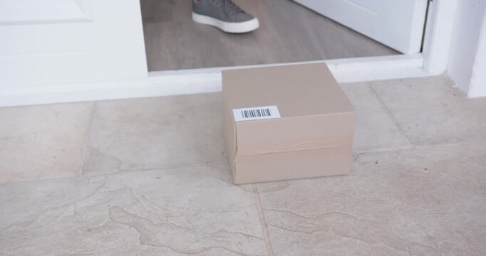 African American man stepping at door opening scanning parcel barcode with phone lifting box inside