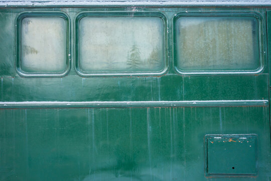 Aged green train car exterior with frosted windows, displaying weathered textures.